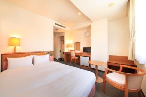 a hotel room with a bed and a desk at Hotel Green Selec in Sendai