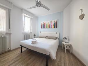 a white bedroom with a bed and a ceiling fan at B&B Color Rovereto in Rovereto