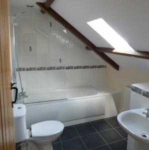 a bathroom with a tub and a toilet and a sink at Beacons View Farm Cottages in Merthyr Cynog