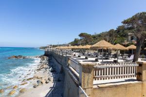 a beach with chairs and umbrellas and the ocean at Camping Residence Costa Verde in Ricadi