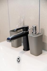 ein Waschbecken im Badezimmer mit einem Wasserhahn neben einer Tasse in der Unterkunft N17 Hotel in Poltawa + 90 Fotos