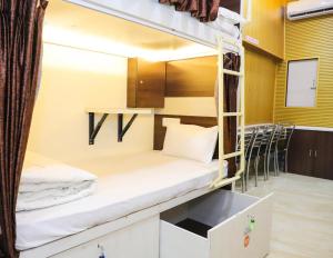 a room with bunk beds with a table and chairs at Mithila Dormitory in Navi Mumbai