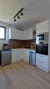 a kitchen with white cabinets and stainless steel appliances at Apartment Karlštejn Castle View in Karlštejn