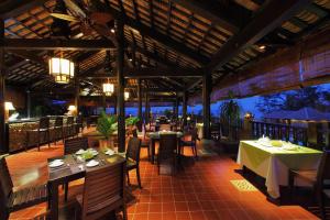 a restaurant with tables and chairs and a view of the ocean at Poshanu Boutique Resort in Mui Ne