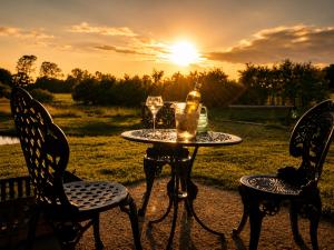 a table with two chairs and a bottle and two glasses at Mountbatten Shepherds hut & Buckhurst Shepherds hut in Ashford