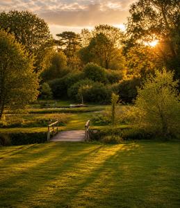 a wooden bridge in a park with the sun setting at Mountbatten Shepherds hut & Buckhurst Shepherds hut in Ashford +82 photos