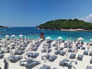 a bunch of chairs and umbrellas on a beach at Vila Oriku in Sarandë