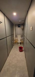 a small bathroom with a toilet and a red bucket at Hottel! Basera in Bhubaneshwar