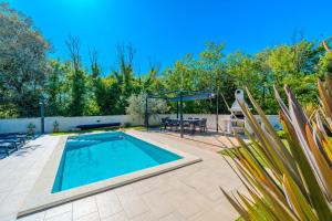 a swimming pool in a backyard with a table and chairs at Modern Villa with Pool and Wellness in Sveti Vid-Miholjice +44 photos