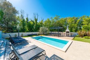 a swimming pool with chairs and a table and a grill at Modern Villa with Pool and Wellness in Sveti Vid-Miholjice