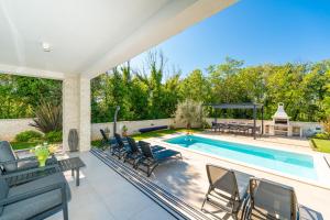 a swimming pool with chairs and a table next to a swimming pool at Modern Villa with Pool and Wellness in Sveti Vid-Miholjice