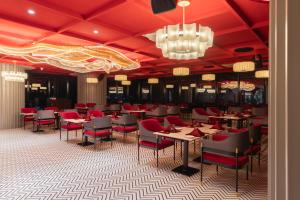 a dining room with tables and chairs and a chandelier at Hotel Lohara Inn in Chandrapur