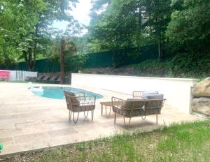 a patio with two chairs and a table next to a pool at Le Mas des Sources - Appartement in Vals-les-Bains