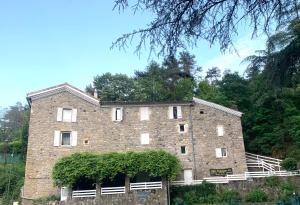 a large brick building with trees in the background at Le Mas des Sources - Appartement in Vals-les-Bains