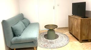 a living room with a blue couch and a tv at Le Mas des Sources - Appartement in Vals-les-Bains