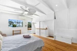 a white bedroom with a bed and a ceiling fan at Pet friendly100m to Beach and Cafe by Custom Bnb Hosting in Urangan +26 photos