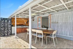 a wooden table and chairs on a patio at Pet friendly100m to Beach and Cafe by Custom Bnb Hosting in Urangan