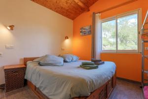 a bedroom with a bed with an orange wall at Gite Du Mouredon in Vallon-Pont-dʼArc
