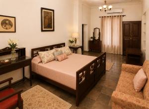 a bedroom with a bed and a desk and a couch at AM Hotel Kollection- Maangarh, Ratlam in Sailāna