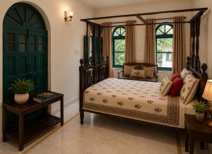 a bedroom with a canopy bed and two windows at AM Hotel Kollection- Maangarh, Ratlam in Sailāna