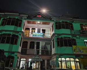 a green building with a balcony at night at lake view resort kafnoo in Yangpa