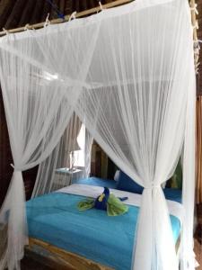 a bedroom with a bed with white curtains at Green Cottage Lembongan by ABM in Nusa Lembongan