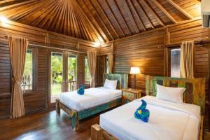 two beds in a room with wooden walls at Green Cottage Lembongan by ABM in Nusa Lembongan