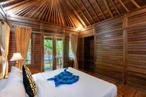 a bedroom with a bed in a room with wooden walls at Green Cottage Lembongan by ABM in Nusa Lembongan