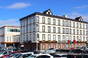 a large white building with cars parked in a parking lot at Natural SPA, Kanazawa Hotel Yumenoyu in Kanazawa