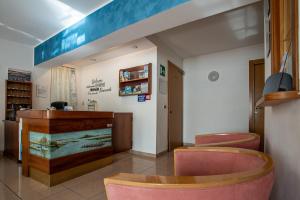 ein Wartezimmer mit rosa Stühlen und einem Tresen in der Unterkunft Hotel Eliani in Grado