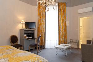 - une chambre avec un lit, un bureau et une télévision dans l'établissement Domaine d'Auriac - Relais & Châteaux, à Carcassonne