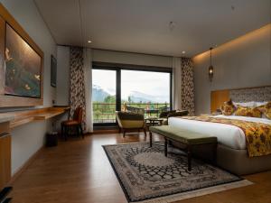 a hotel room with a bed and a large window at Mountnoor Sarovar Premiere Pahalgam in Anantnāg +85 photos