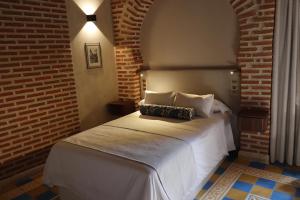 a bedroom with a white bed with a brick wall at Posada San Miguel Arcángel Experience in Arévalo