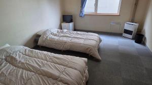 a bedroom with two beds and a window at Shimano Yado Rishirikuru in Rishiri