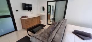a room with a couch and a tv and a mirror at Nua Tone Riverside in Thalang
