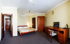 a bedroom with a bed and a desk with a computer at Hotel Patriarshyi in Lviv
