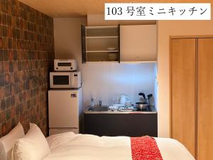 ein Zimmer mit Bett und eine Küche mit Mikrowelle in der Unterkunft Angelroad Hotel in Tonosho