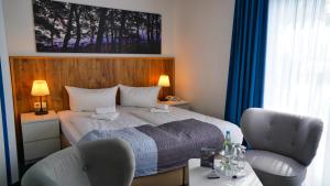 a hotel room with a bed and two chairs at Hotel & Restaurant Seebrücke in Zingst