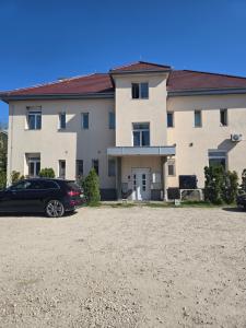 a car parked in front of a large building at Apartman Wegele in Teslić