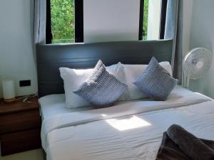 a bedroom with a bed with blue and white pillows at Nua Tone Riverside in Thalang