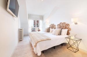 a white bedroom with two beds and a tv at Apartamento Platas Centro in Ribadesella