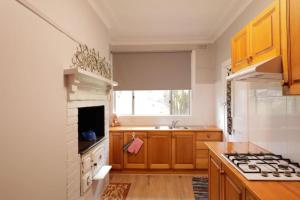 a kitchen with wooden cabinets and a stove top oven at Cosy Sun-Filled Cottage in Tenterfield