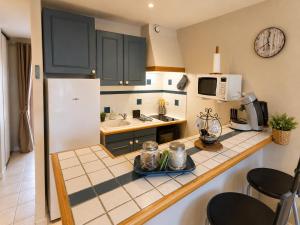 a kitchen with black cabinets and a white refrigerator at Grand Studio Tout Confort pour 3 personnes Linge en option in Barcelonnette