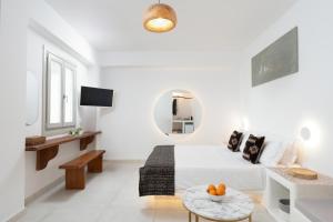 a white bedroom with a bed and a table at Lumera Suites in Firostefani