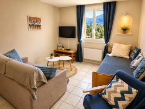 a living room with a couch and a tv at Grand Studio Tout Confort pour 3 personnes Linge en option in Barcelonnette