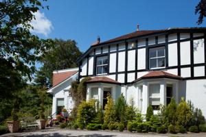 a white and black house with trees and plants at Tir y Coed Country House in Conwy