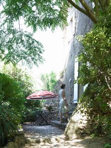 a woman standing under an umbrella next to a building at Château de la Motte in Marcorignan