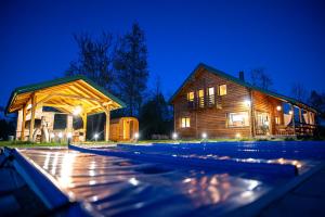 a wooden house with a swimming pool at night at Lika View house in Gospić