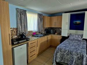 a bedroom with a bed and a kitchen with wooden cabinets at Danrit Guesthouse - Uncapped wifi in Roodepoort