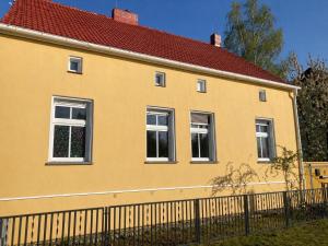 a yellow house with white windows and a fence at Ferienhaus Schorfheide Kamin Sauna Naturgarten nahe Seen & Wildpark in Schorfheide +12 photos